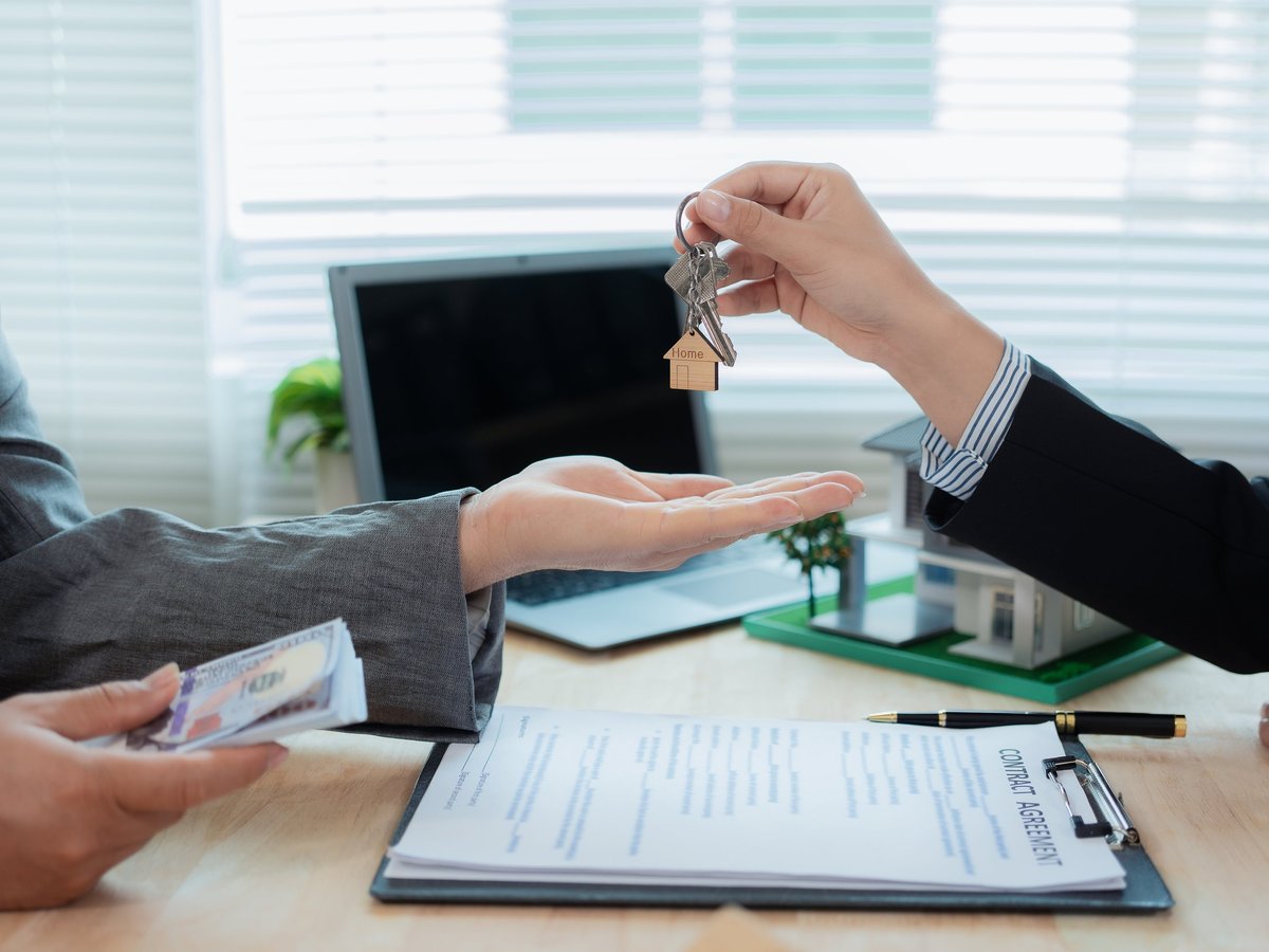 Hands passing keys during a property handoff representing inherited land